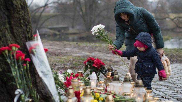A mother and child lay flowers at a memorial. Photo: MINDAUGAS KULBIS
